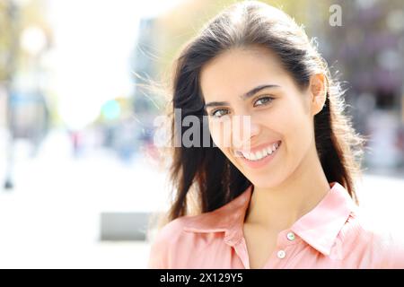 Ritratto di una donna felice con un sorriso bianco che posa in piedi per strada Foto Stock