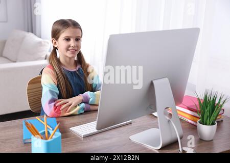 E-learning. Ragazza carina che usa il computer durante una lezione online a tavola in casa Foto Stock