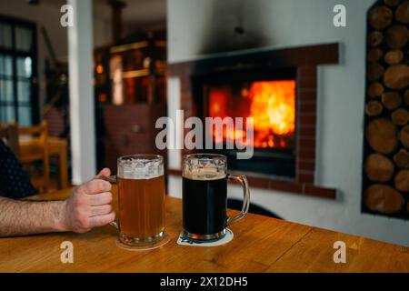 Due bicchieri di birra, chiara e scura, in un pub vicino al caminetto Foto Stock