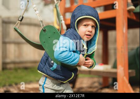 Il bambino che balla nel parco giochi sulla pancia e guarda la macchina fotografica Foto Stock