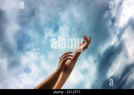 Le mani della donna che raggiungono il cielo con le nuvole Foto Stock