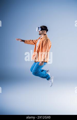 Un uomo con una giacca arancione e pantaloni blu sta saltando nell'aria. Foto Stock