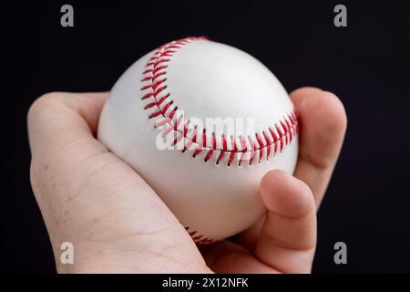 palla da baseball bianca legata con filo rosso, una vera palla da baseball rotonda in primo piano Foto Stock