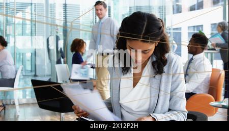 Immagine di un tunnel con uno schema senza cuciture su una donna d'affari birazziale che legge documenti in ufficio Foto Stock