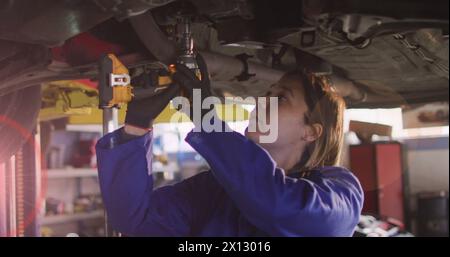 Immagine di macchie di luce su una donna birazziale che ripara l'auto Foto Stock
