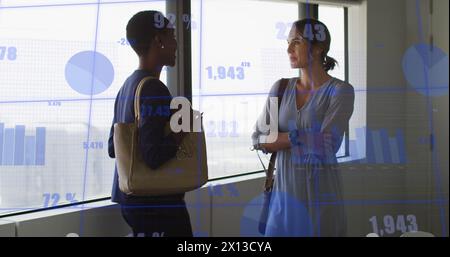 Immagine di più grafici e numeri variabili rispetto a diverse collaboratrici che discutono in ufficio Foto Stock