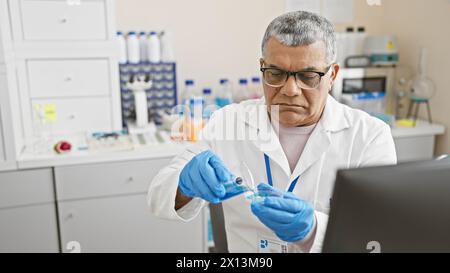 Un uomo maturo in un camice da laboratorio conduce esperimenti in un laboratorio ben attrezzato. Foto Stock