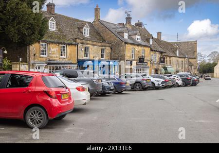 Una trafficata Stow su Wold Street, fiancheggiata da negozi di pietra del Cotswold e auto parcheggiate, un'attrazione popolare per i turisti. La popolare destinazione delle Cotswolds. Foto Stock