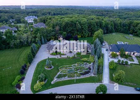 Scopri il fascino delle case di lusso da un milione di dollari in affascinanti paesaggi crepuscolari. Esplorate gli splendidi giardini e i giardini sul retro sotto la notte Foto Stock