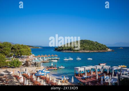 Vacanze al mare nella soleggiata Albania meridionale. Splendido paesaggio diurno dell'isola di Ksamil, del Mar Ionio, della costa sabbiosa, dei moli con lettino solare nella riviera albanese. Foto Stock