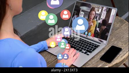 Immagine delle icone del profilo che fluttuano sulla vista posteriore della donna che riceve una chiamata immagine sul laptop in un bar Foto Stock