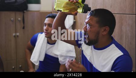 Immagine delle icone delle cellule covid-19 sopra il giocatore di calcio ispanico maschile che gli mette l'acqua sul viso Foto Stock