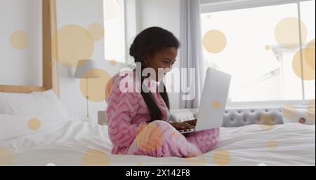 Immagine di punti luminosi e percorsi su una ragazza afroamericana che usa un computer portatile Foto Stock