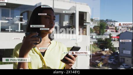 Immagine di icone e numeri dei social media sulla donna birazziale che usa lo smartphone Foto Stock