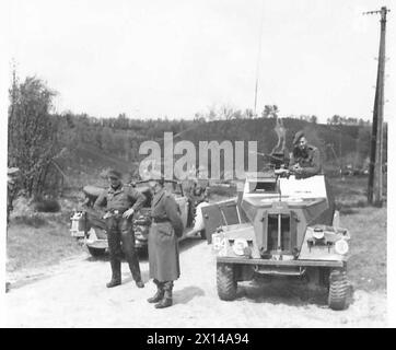 I TEDESCHI CERCANO LA PACE AD AMBURGO - i piloti tedeschi aspettano i tedeschi al fianco di un'auto da corsa britannica British Army, 21st Army Group Foto Stock