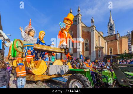 Cantu, Italia - 25 febbraio 2023: Sfilata di Carnevale, con carro a figura allegorica (Alice nel paese delle meraviglie), folla e Chiesa dei Santi Michele e Bla Foto Stock