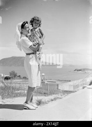 AL CAMPO DI INTERNAMENTO STANLEY, HONG KONG. AGOSTO E SETTEMBRE 1945. Sorella Harrington, che viene da Slade Green, Kent, ha curato gli internati malati nel campo Stanley, Hong Kong. È con Baby Rolanda Jones, di 3 anni, 1/2. Rolanda perse suo padre durante la guerra e nacque nel campo durante un raid aereo accidentale giapponese, aiutato nel mondo da sorella Harrington. Oltre ai suoi compiti di infermieristica, sorella Harrington ha servito nelle cucine e ha aiutato nelle vasche di lavaggio del campo. Durante il suo internamento ha subito un braccio e una gamba rotti, Foto Stock