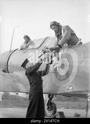 GLI OCCHI FOTOGRAFICI DELLA FLOTTA. 4 MARZO 1943, ROYAL NAVAL AIR STATION, STRETTON, LANCS, SI SENTE POCO DEI FOTOGRAFI CHE VOLANO CON AEREI NAVALI PER OTTENERE I REGISTRI DELLE ATTIVITÀ NEMICHE E DEI RISULTATI DEI NOSTRI ATTACCHI. - Un rating che consegna la telecamera al fotografo dell'aereo Foto Stock