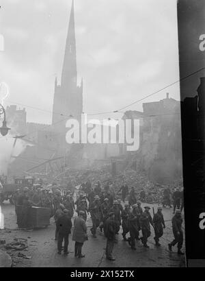 OPERAZIONE MOONLIGHT SONATA: BOMB DAMAGE IN COVENTRY, NOVEMBRE 1940 - le truppe marciano attraverso il centro della devastata Coventry il 16 novembre 1940. La cattedrale può essere vista sullo sfondo. Gran parte della città fu distrutta durante i gravi raid aerei tedeschi nella notte del 14-15 novembre 1940 Foto Stock