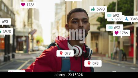 Immagine di numeri che cambiano, icone nelle barre di notifica sopra l'uomo birazziale in piedi sulla strada Foto Stock