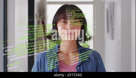 Immagine di un linguaggio informatico multicolore su una donna asiatica in piedi a casa Foto Stock