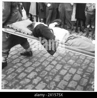 IL PREZZO DELLA VITTORIA - fuori dal 88th British General Hospital. Una bomba a V è caduta e i casultati civili arrivano osservati da folle ansiose British Army, 21st Army Group Foto Stock