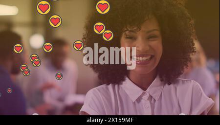 Immagine di cuori che fluttuano sopra una donna afroamericana felice Foto Stock