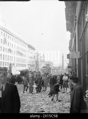 LA GRAN BRETAGNA SENTE LA NOTIZIA DELLA FINE DELLA GUERRA JAP: CELEBRANDO LA VITTORIA IN GIAPPONE, LONDRA, INGHILTERRA, Regno Unito, 15 AGOSTO 1945 - i civili camminano tra le pile di carta strappata che sono state gettate dalle vetrine degli uffici, in Lower Regent Street, Londra, per celebrare la firma della Pace con il Giappone. Un ragazzo può essere visto giocare con i mucchi di carta, e i volti di molte delle persone che aspettano alla fermata dell'autobus sono oscurati dai rottami che cadono. Sullo sfondo, dietro a molti veicoli (tra cui un carro trainato da cavalli), la colonna di Nelson è appena visibile. È probabile che questa foto Foto Stock