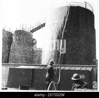 I vigili del fuoco dell'esercito britannico gestiscono tubi flessibili e tubi in schiuma per spegnere la benzina in fiamme, collegare i sistemi di erogazione e dirigere la schiuma sulla superficie. Foto Stock