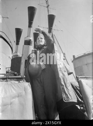 A BORDO DEL DESTROYER HMS KELVIN. 1941. - Un membro di un equipaggio di pistole che indossa un casco antiesplosione che riceve ordini dal ponte Foto Stock