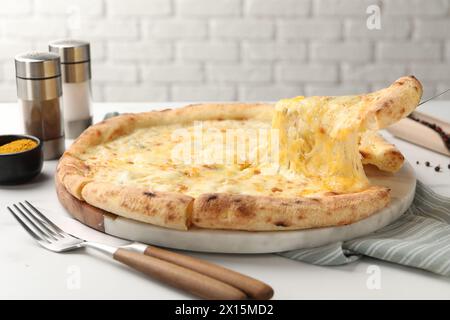 Prendere un pezzo di deliziosa pizza al formaggio al tavolo bianco Foto Stock
