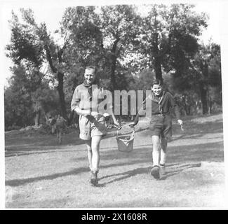 ROMA : SCOUT RALLY - Jin (conosciuto come 'Little' Jim per differenziarlo da 'Big' Jim l'americano) un esploratore inglese che serve con il R.A.M.C. riceve una mano con un secchio d'acqua di tela da un giovane esploratore italiano che è uno dei preferiti dell'equipaggio della Allied Service Rover, in quanto parla bene inglese British Army Foto Stock