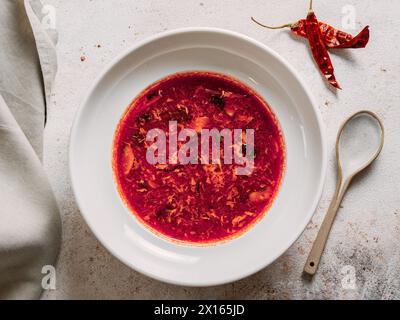 Borscht tradizionale di zuppa rossa a base di barbabietola. Zuppa nazionale russa e Ucraina, cucina, cibo. Gustosa zuppa di barbabietole con verdure nel recipiente su sfondo pastello neutro. Vista dall'alto, disposizione piatta Foto Stock