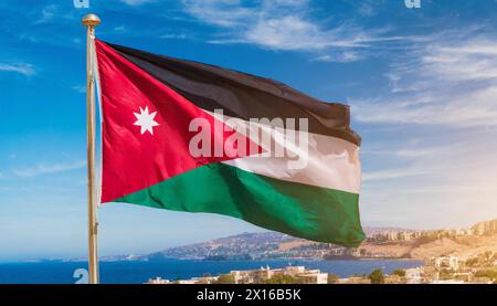 Die Fahne von Jordanien flattert im Wind, isoliert gegen blauer Himmel Foto Stock