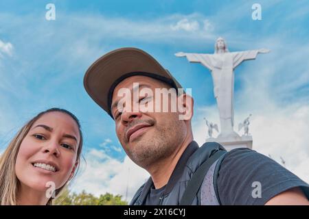 Un uomo e una donna stanno posando per un'immagine davanti ad una statua di Gesù Cristo, archi di Acuchimay, Ayacucho. Perù Foto Stock