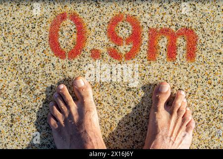 due piedi all'ingresso della piscina con un'indicazione di profondità di 0,9 metri. Foto Stock