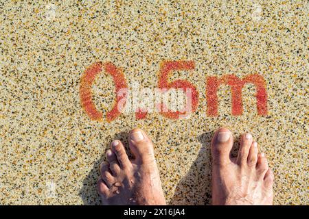 due piedi all'ingresso della piscina con un'indicazione di profondità di 0,5 metri Foto Stock