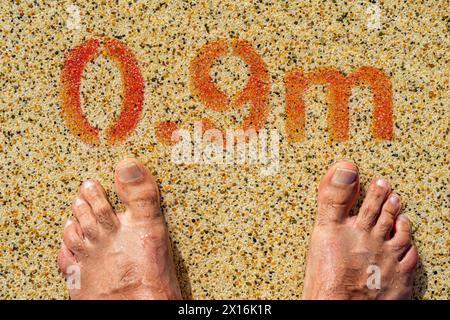 due piedi all'ingresso della piscina con un'indicazione di profondità di 0,9 metri. Foto Stock