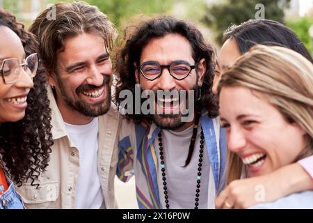 Il colpo alla testa di un gruppo di amici si è abbracciato a ridere insieme e a divertirsi all'aria aperta. Foto Stock