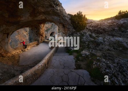 Un uomo che si gode la calma di una grotta vuota nella natura all'alba Foto Stock