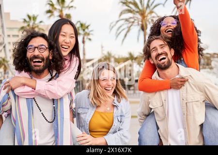 Gruppo interrazziale di amici che si divertono, fanno i salvadanaio all'aperto durante il viaggio in un paese tropicale Foto Stock