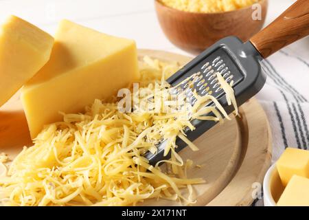 Grattugiato, pezzi interi di formaggio e grattugia sul tavolo, primo piano Foto Stock
