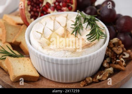 Sali a bordo con gustosi camembert al forno, crostini, uva, noci e melograno sul tavolo, primo piano Foto Stock