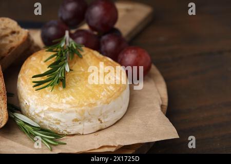 Gustoso camembert, uva e rosmarino al forno su tavola di legno, primo piano. Spazio per il testo Foto Stock