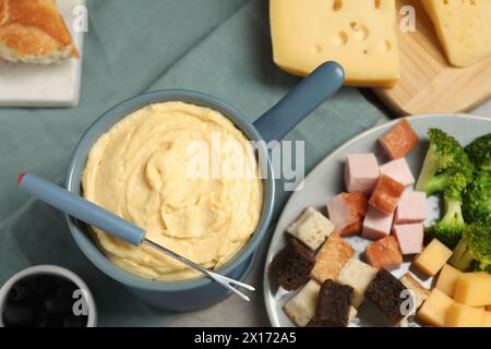 Gustoso formaggio fuso in fonduta, forchetta e spuntini sul tavolo, piatto Foto Stock