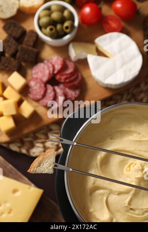 Fonduta con gustoso formaggio fuso, forchette e diversi spuntini sul tavolo, vista dall'alto Foto Stock