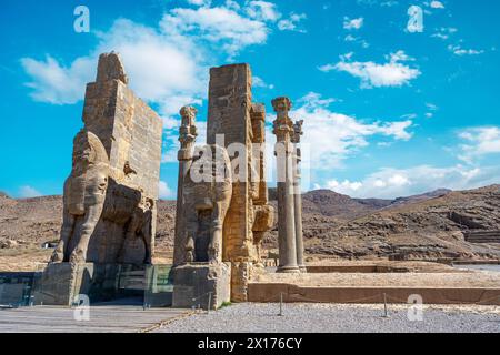 Imponenti statue di Lamassu si ergono alte, gettando intricate ombre tra le antiche rovine di Persepoli, Iran. Immortalato in una giornata intensa con la sk blu Foto Stock