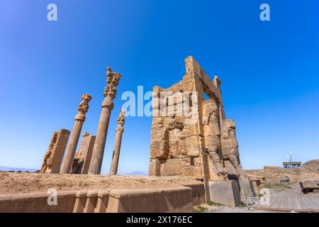 Imponenti statue di Lamassu si ergono alte, gettando intricate ombre tra le antiche rovine di Persepoli, Iran. Immortalato in una giornata intensa con la sk blu Foto Stock