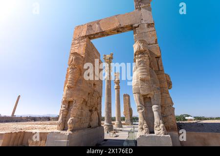 Imponenti statue di Lamassu si ergono alte, gettando intricate ombre tra le antiche rovine di Persepoli, Iran. Immortalato in una giornata intensa con la sk blu Foto Stock