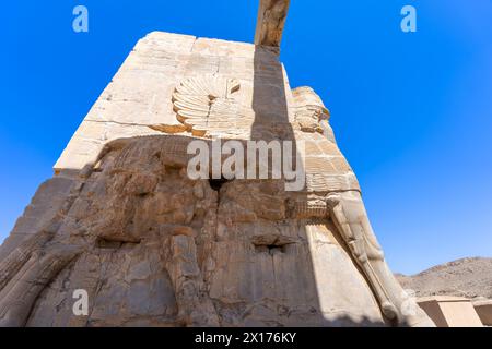 Imponenti statue di Lamassu si ergono alte, gettando intricate ombre tra le antiche rovine di Persepoli, Iran. Immortalato in una giornata intensa con la sk blu Foto Stock